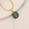 Collar dorado con colgante de cruz de piedra natural verde en un plato blanco - Malaquita