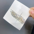 Macro detail of gold-plated leaf hair clip featuring sparkling inlaid rectangular zircons - Feather-Gold