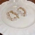 Detailed macro view of elegant white flower hoop earrings on a white ceramic plate - Style 13
