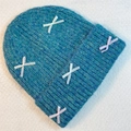 Close-up of peacock blue knitted beanie featuring white and lavender ribbon bow details - Teal