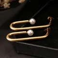 Pendientes dorados minimalistas en forma de U con elegantes perlas sobre terciopelo negro - Dorado