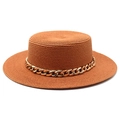 Detailed close-up of a flat-top straw boater hat featuring a bold gold metal chain band - Caramel color