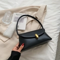 Retro black leather underarm bag with gold metal buckle on beige blazer background - Black