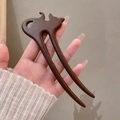 Close-up of deep brown wooden hair pin with a cat-shaped carving and double-prong design - Long-legged Cat (Zebrawood)