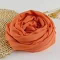 Detailed texture of orange cotton linen scarf folded into a rose shape on a woven mat - 190x100cm / Orange