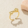 Detail of a polished gold-plated bow-shaped open ring with 3D twisted metallic texture - Adjustable Open / Gold Bowknot