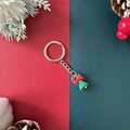 Christmas keychain featuring a green bell with a red bow on a festive background - Christmas Bell