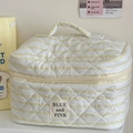 Close-up of quilted yellow stripe toiletry bag with BLUE and PINK label in a soft scene - Makeup Bag / Yellow