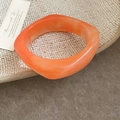 Detailopname van een oranje harsarmband met marmeren textuur en onregelmatige hoeken - Oranje