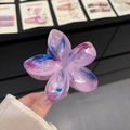 Detail of translucent frangipani hair claw clip with marble texture in hand - 8cm / Purple