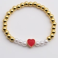 Bracciale a sfere dorate con perle bianche e ciondolo a cuore rosso su superficie riflettente - Rosso