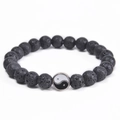 Close-up of black volcanic lava beads and silver Yin Yang charm on an elastic bracelet - Black Lava Stone (Tai Chi Pendant)