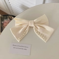 Elegant cream satin bow hair claw clip with white pearl accents on white table - Creamy White Pearl Double Bow Spring Clip