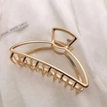 Detail of a large gold metal hair claw clip with geometric cutout design on white fabric - KC Gold-Half Moon