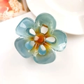 Close-up of translucent blue floral hair claw clip with amber center and gold metal spring - 5-Petal Flower Foggy Blue