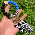 Close-up of cow print bead bracelet keychain with Mama cow tag and blue silicone beads - Blue/Cow Print