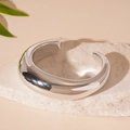 Detailopname van een zilveren geometrische open armband op een witte ruwe natuursteen - Glad Oppervlak (HB3353) / Zilver