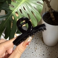 Close-up of a glossy black French claw clip held by hand in a natural home setting - Glossy Black