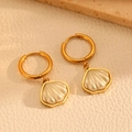Detail of gold hoop earrings with cream shell pendants on textured beige leather - Gold Scalloped Shell Hoop Earrings (H216)