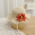 Close-up of beige woven straw hat with lace edges and a vibrant orange flower decoration - Straw Hat / Beige