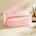Pink mesh makeup bag with golden slogan and handle shown with skincare items - Pink