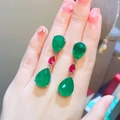 Detail of pear-shaped emerald and ruby stone earrings displayed on hand for size - Style A Emerald Green