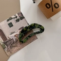 Detail einer dunkelgrünen Schildpatt-Haarklammer mit goldenem Logo auf dem Tisch - Grünes Schildpatt