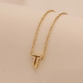 Macro shot of gold initial T pendant with sparkling crystals on minimalist chain - Letter T