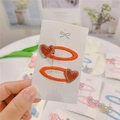 Pair of orange fabric hair clips with red rhinestone hearts on a white card display - Red Heart BB Clips (Pair)