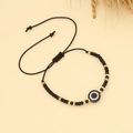Detail of adjustable black woven bracelet featuring blue evil eye charm and gold beads - Type F-Black Evil Eye