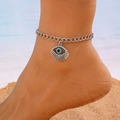 Silver evil eye anklet with blue rhinestones worn by a model on a sunny beach background - Layered Silver Evil Eye Chain Style (White K K-896)