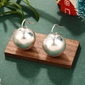Boucles d'oreilles boules argentées minimalistes sur fond festif avec des feuilles vertes - Argent