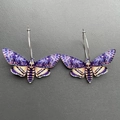 Close-up of acrylic moth earrings with skull pattern and silver rings on grey background - K53 Purple Moth