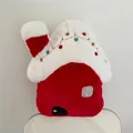 Detail of red and white house-shaped Christmas plush pillow with colorful pom-poms on chair - Christmas House