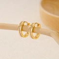 Detail of gold-plated hoop earrings with micro-set zircon rows on a wooden stand - EH411028