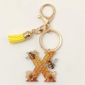 Detail of honey bee letter K acrylic keychain with golden clasp and yellow leather tassel - Letter X