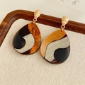 Dettaglio di orecchini a goccia in resina stile pittura a olio su un vassoio di lino - Patchwork Oro-Nero (Perno in Argento)