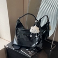 Detail of black glossy tote bag with bow accent and white cloud plush charm - Black