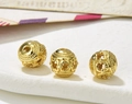 Three hollow golden vintage beads for DIY jewelry making displayed on a textured surface - Style 29