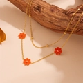 Close-up of double-layer gold necklace with orange flower pendants on a wooden branch - Red Shell Necklace (L505)