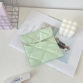 Close-up of a light green quilted sanitary pouch with pink heart button on a white table - Fruit Green Plaid