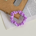 Elegant purple satin scrunchie with a silky finish for hair styling on a warm desk background - Purple
