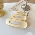 Macro detail of three matte cream oval hair clips stacked on a minimalist background - Creamy Yellow