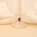 Elegant gold chain necklace with a deep red faceted glass heart pendant on a glass display - Deep Purple