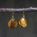 Detail of wire-wrapped tiger eye drop earrings hanging on a natural wooden branch - Yellow Brown Tiger Eye Style (ER1060-3)