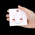 Hand holding Santa Claus moon stud earrings with festive red white and gold enamel finish - Moon Santa Style 1