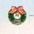 Detailed view of a 6.5cm Christmas wreath cake topper with golden star and red bow - Gold Bow Pine Wreath Style
