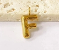Macro shot of 3D golden puffed letter F pendant on beige stone and white background - Letter-F / Steel