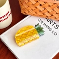Cute yellow pineapple hair claw clip with green leaves on a white book display - Pineapple