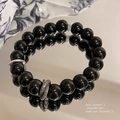 Macro shot of black obsidian bead bracelet with silver spacers reflecting on mirror - Black/Obsidian Style